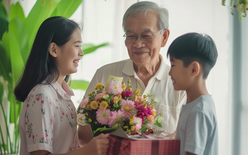 Grandchildren presenting a colorful bouquet of flowers to their grandfather