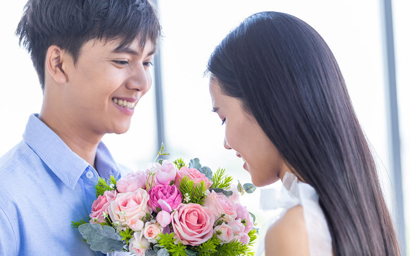 Man giving a pink and red rose bouquet to a woman.