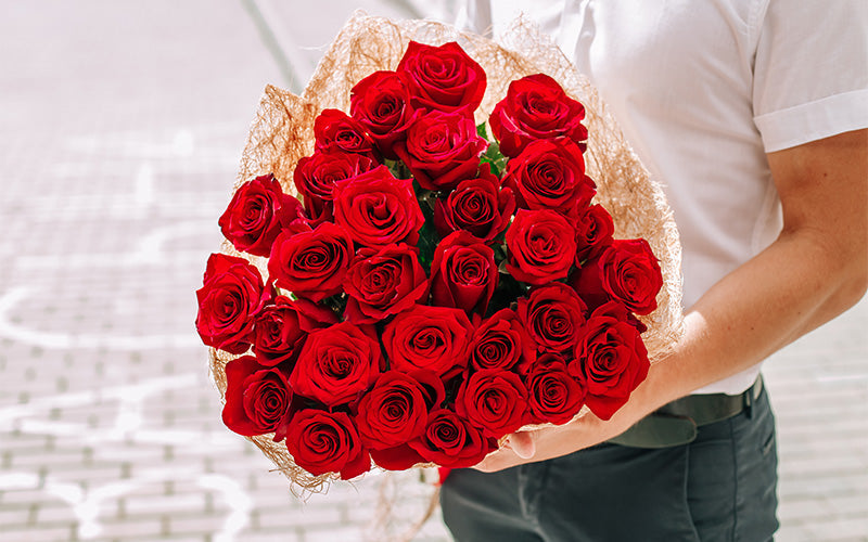 Man holding a large bouquet of vibrant red roses