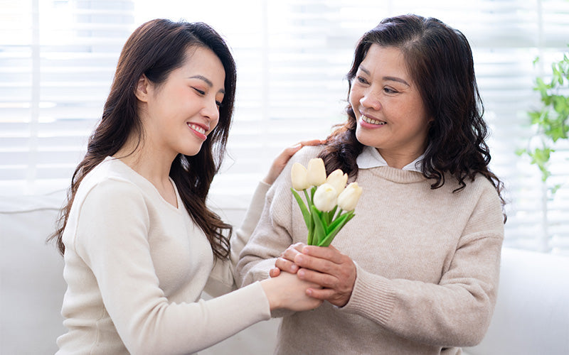 Person giving bouquet of tulips indoors.