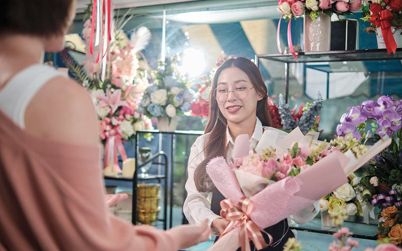 Florist handing a bouquet to a customer in Singapore.