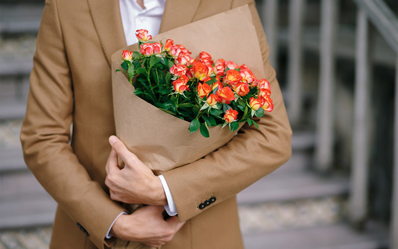 A close-up of a person in a tan blazer holding a large bouque