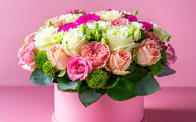 Vibrant fresh rose arrangement in a pink gift box.